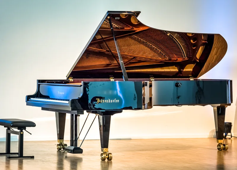 A Bösendorfer concert grand piano with its lid open on a stage